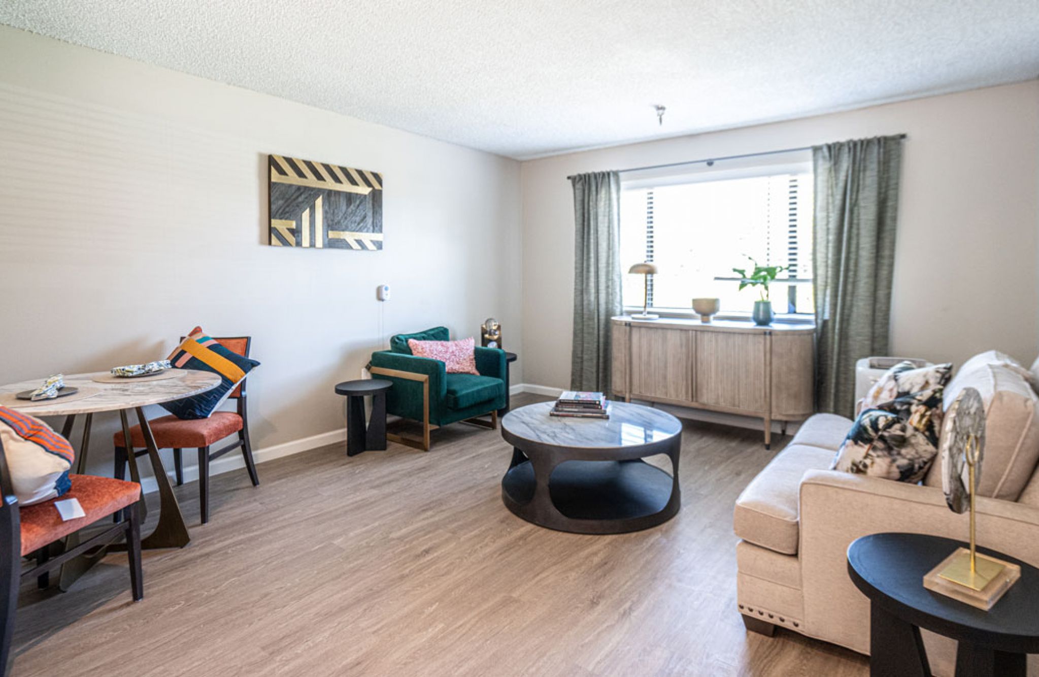 Bright living room with modern furniture, dining area, and green curtains—perfect for comfortable senior living at Saga Senior Living.