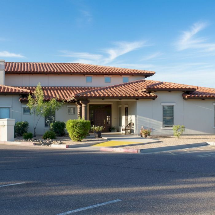 Barton House is a single-story building with a red tile roof, surrounded by shrubs, under a clear blue sky.