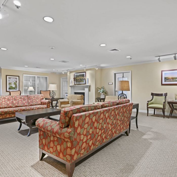 A spacious living room in Tarina of Cypresswood with patterned sofas, armchairs, coffee tables, and framed art on light-colored walls.
