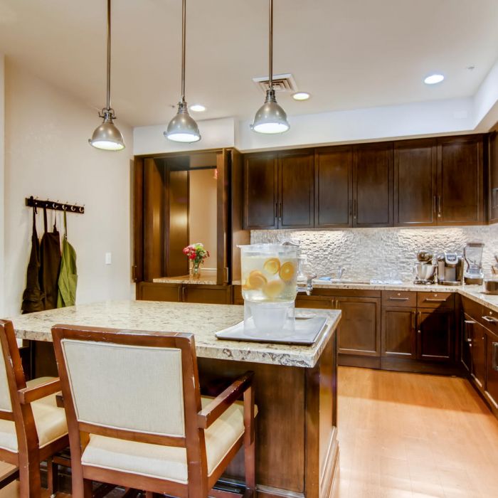 Modern kitchen at Terraces at Kingwood features dark wood cabinets, marble island, and elegant pendant lights—perfect for senior living.