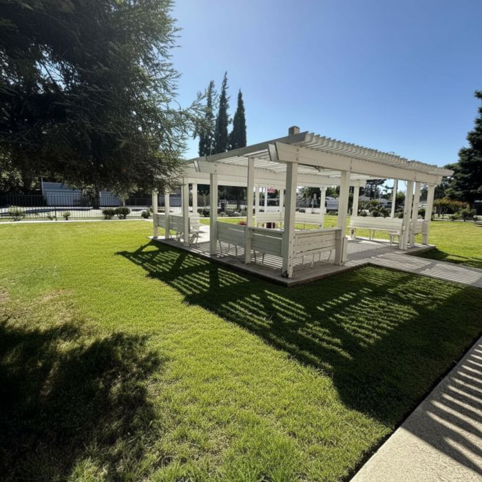White wooden gazebo on a sunny lawn, with shadows and trees—perfect for a Tarina of Stockton summer afternoon under clear blue skies.