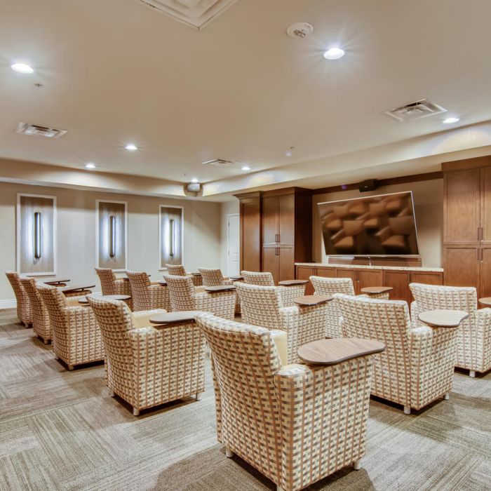 Cozy theater room at Terraces at Kingwood features cushioned seats, wood paneling, and soft lighting—perfect for senior living enjoyment.