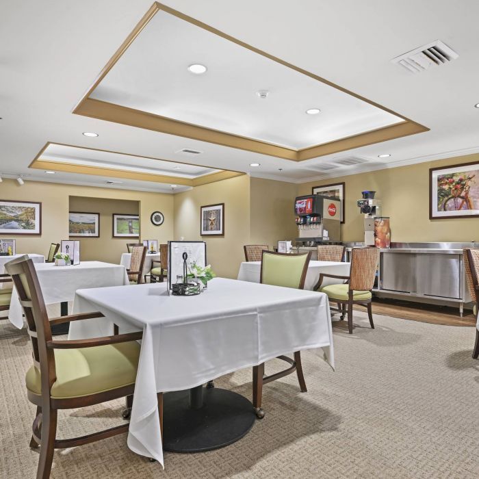 Dining area at Tarina of Cypresswood with tables, chairs, wall art, a beverage station, and warm lighting.