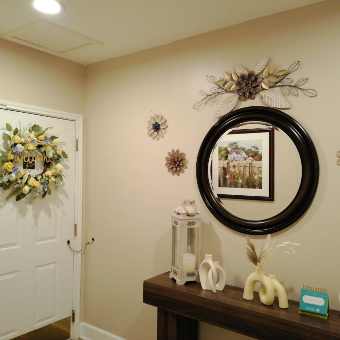 Hallway in Tarina of Kingwood with a decorated door, mirror, floral wall art, and a console table adorned with ornaments.