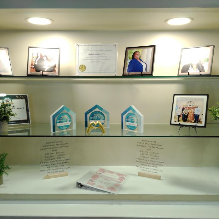 A display shelf at Tarina of Kingwood with framed photos, awards, decorative plants, and printed information sheets.