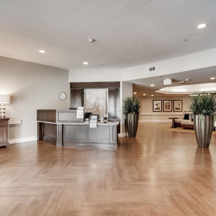 Modern lobby at Terraces at Kingwood with wood flooring, reception desk, large plants, and decorative furniture for senior living.