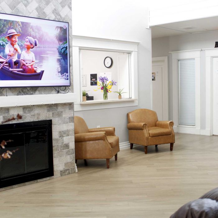 A cozy lobby with armchairs, a fireplace, and a TV showing an animated movie above the mantel.