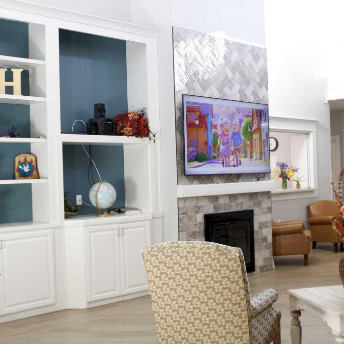 A cozy living room with built-in shelves, a TV above the fireplace, and autumn decorations.