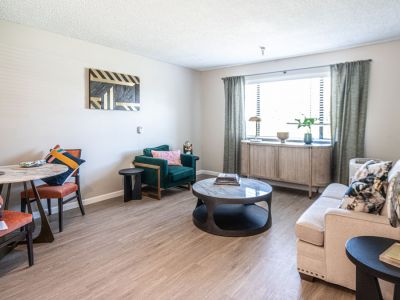 Bright living room with modern furniture, dining area, and green curtains—perfect for comfortable senior living at Saga Senior Living.