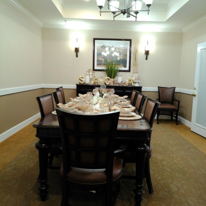 Elegant dining room in Tarina of Kingwood with dark wood table, eight chairs, wall art, and a modern chandelier overhead.