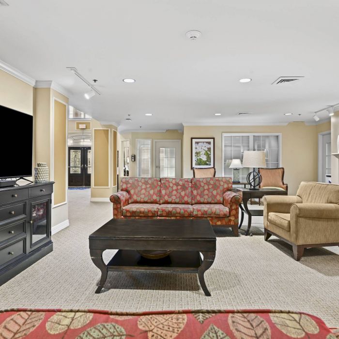 Bright living room in Tarina of Cypresswood with sofas, a TV, fireplace, coffee table, and framed art on beige walls.
