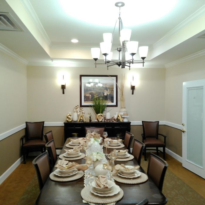 A formal Tarina of Kingwood dining room set for a meal, with elegant place settings and a chandelier overhead.
