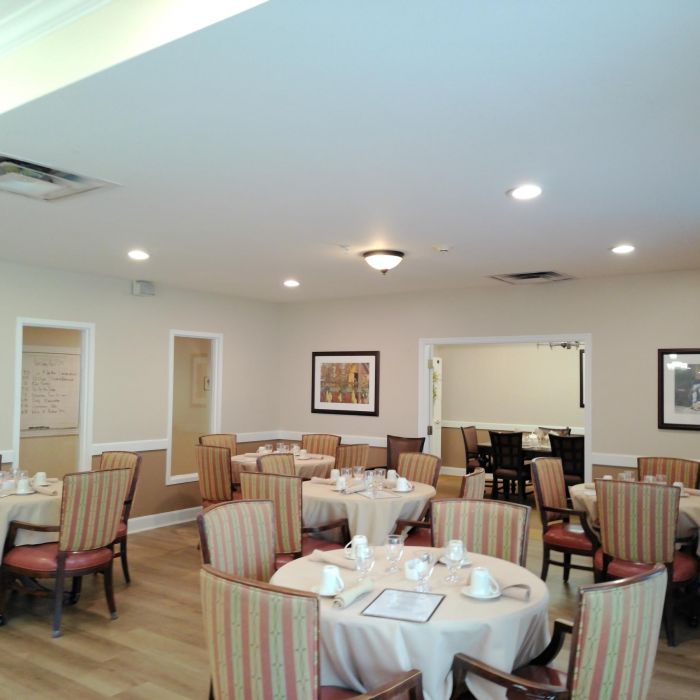 Dining room at Tarina of Kingwood with round tables, set for a meal, surrounded by chairs and framed art on the walls.