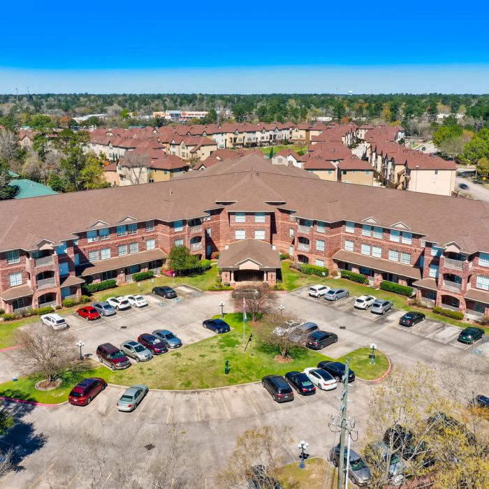 Aerial view of The Terraces at Kingwood, a large brick assisted living complex with circular parking and trees.